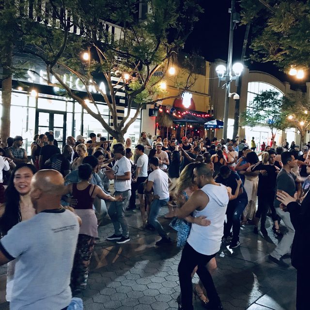 A crowd dancing salsa outdoors at a night-time social