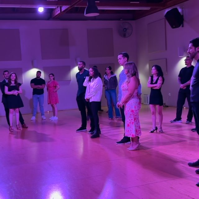 Dancers lined up in a purple-lit studio at a Salsa Dance LA workshop