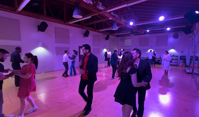 Couples dancing salsa and bachata under purple lights