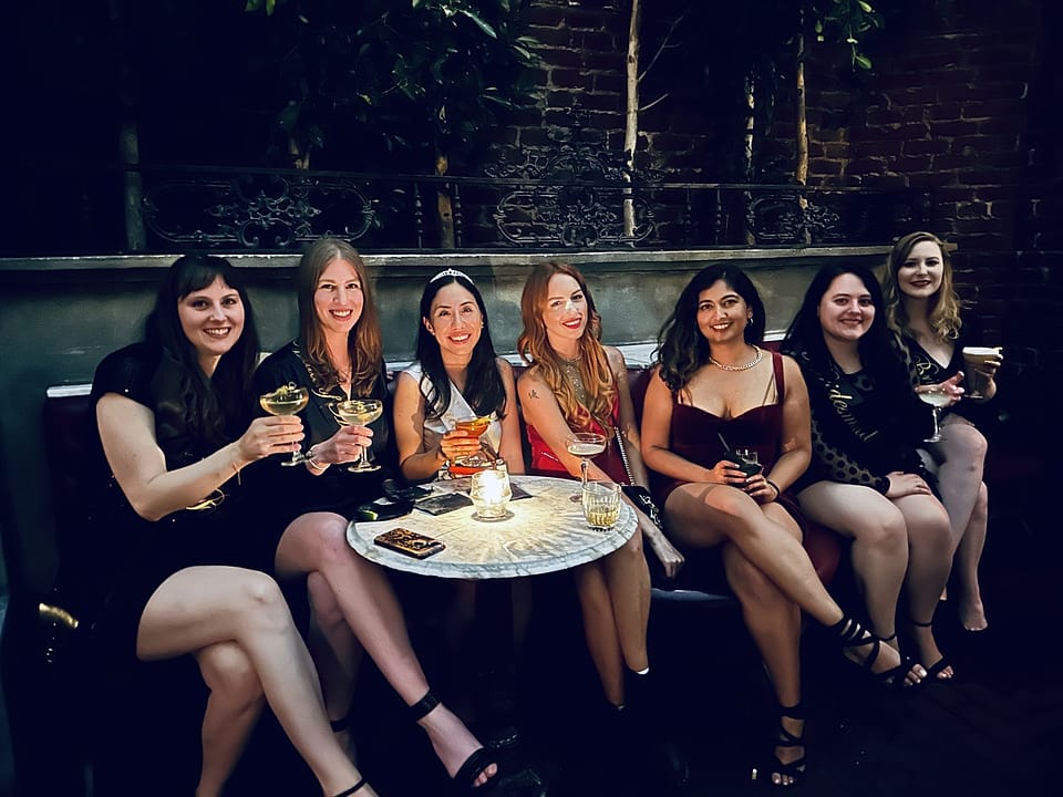 A bachelorette group raising coupes at a candlelit table