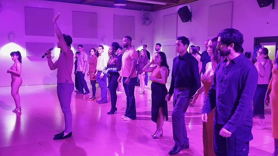 An instructor leading a packed salsa lesson from the front of the room at Rhythms & Romance in Los Angeles